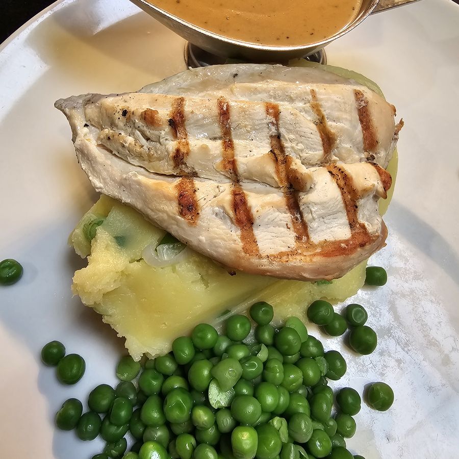 Grilled chicken breast with champ, peas and peppercorn sauce